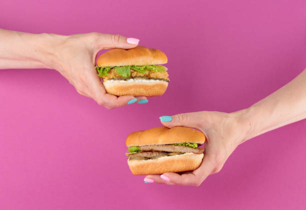 istock Female hand with tasty burger on pink background 1393842939