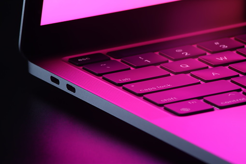 beautiful close up of side view laptop keyboard with red pink color and dark background, low key photography