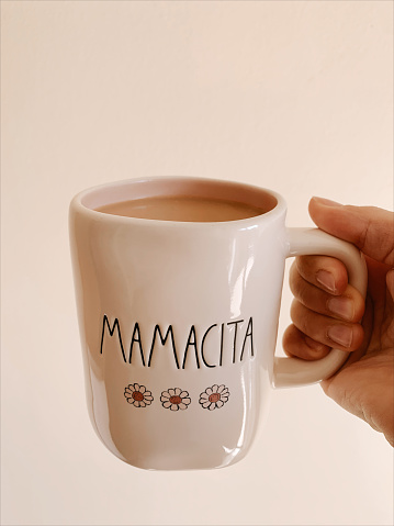 A Mom Holding a Hot Cup of Coffee in a Pink & Cream-Colored Ceramic Mug With the Word 