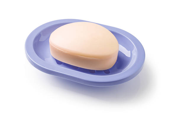 istock Soap on a soap dish isolated on a white background. Oval shaped beige soap bar in a violet blue plastic soapbox for bathroom and shower. Washing hands, toiletries and purity concepts. 1393843300