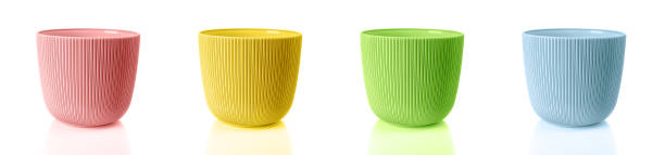 Empty colorful flower pots isolated on a white background. Set of vertical striped planters. Pink, yellow, green and blue plastic containers for indoor plants. Multicolored plant pots.