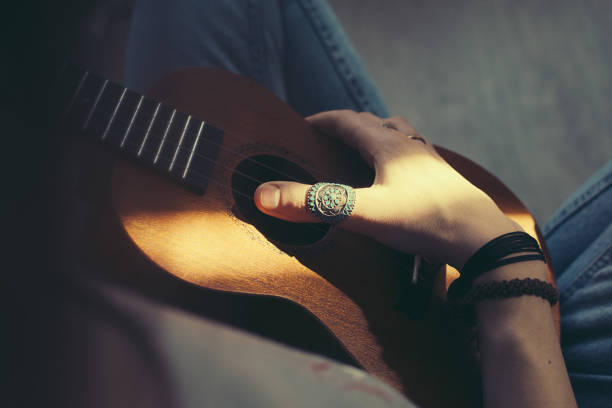 Woman hands with rings playing small guitar ukulele. Musical instrument. Hippie lifestyle.
