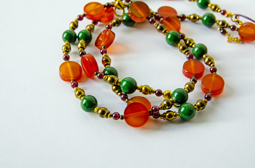 Handmade necklace crafted from beads of orange agate, red garnet and green quartzite intersperced with brass metal beads.