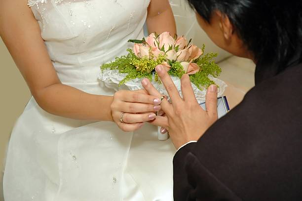 istock Bride putting wedding ring on groom's finger 139384651
