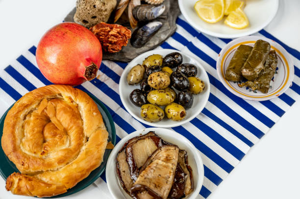 Greek pastry, eggplant,olive and dolmades, pomegranate, lemon on blue striped towel. stock photo
