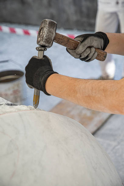 istock Hands of artist who work the marble with hammer and chisel 1393847755