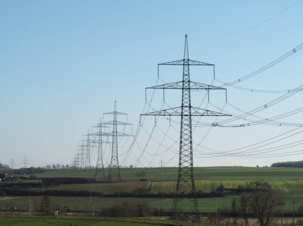 istock Power line with large high-voltage pylons in a green landscape 1393849272