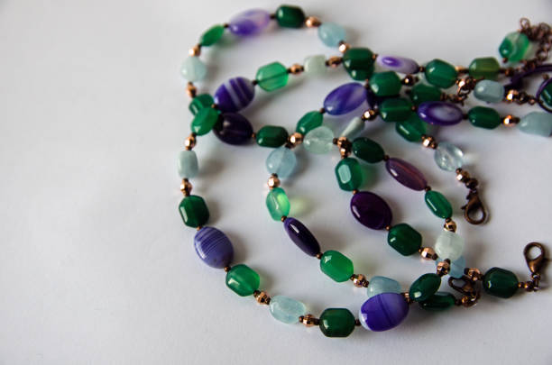 A handmade necklace coiled on a white background made from beads of aquamarine and agate gemstones.