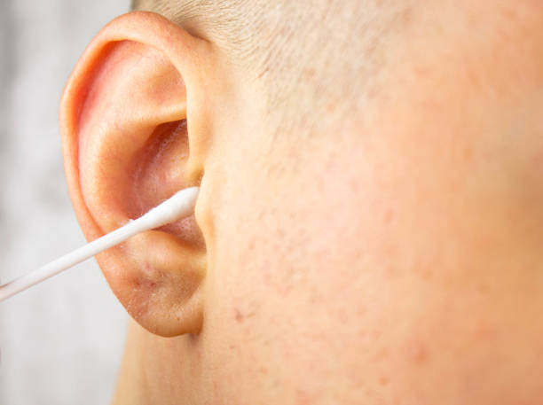 istock A man cleans his right ear close-up. Ear care hygiene. 1393851330