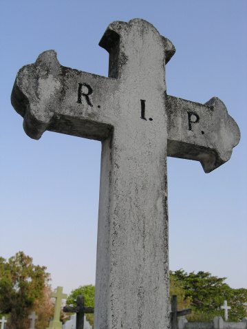 An old cross stands stall in a graveyard.