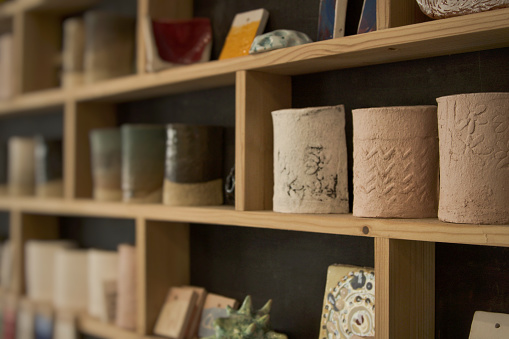 Assorted pottery displayed on wooden shelves with depth of field