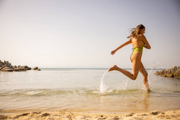 istock Joyful young woman running on the beach 1393854714