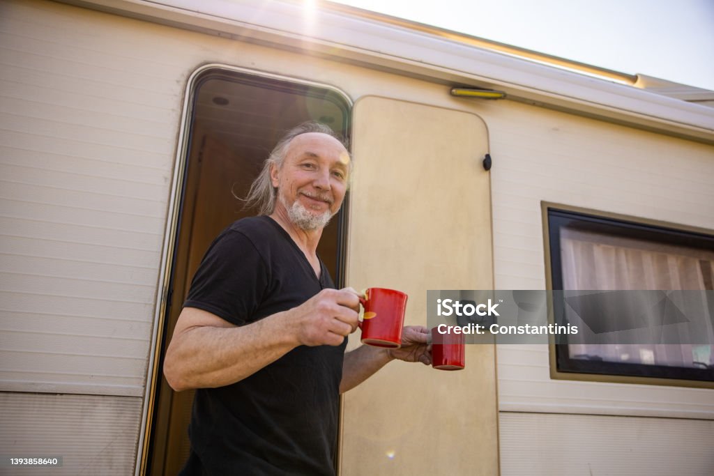 Joyful man holding cup of coffee, during picnic time with hic camper van Carefree Caucasian man carrying two cup of coffee, while enjoy the adventure with his camper van 50-54 Years Stock Photo