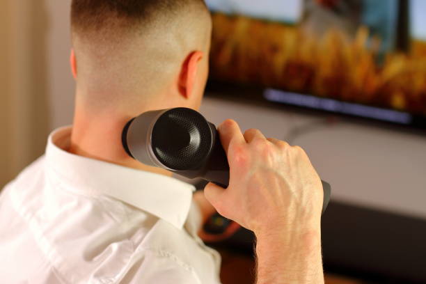 istock Man with massage gun sitting on sofa doing massage, lifestyle staging 1393859880