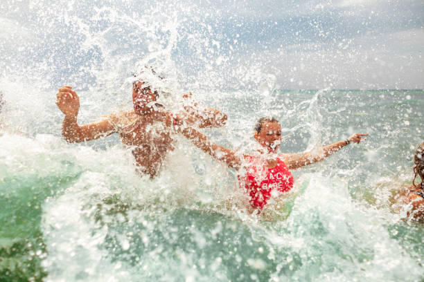 istock Playful siblings having fun in the sea while waves splashing them 1393863434