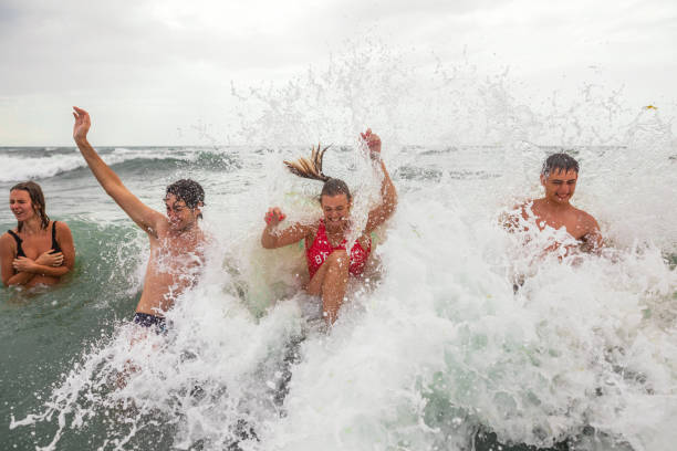 istock Caucasian male and female siblings having fun on vacation while waves splashing them 1393863959