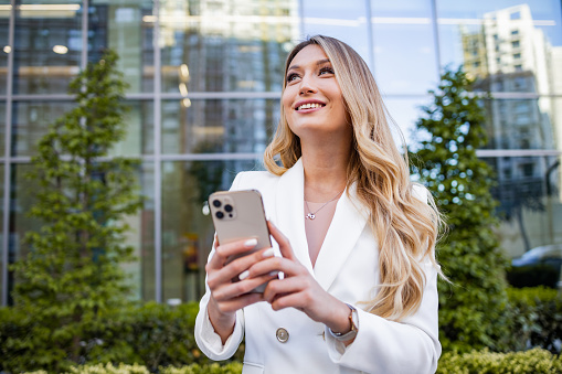 Well dressed woman holding smart phone and smiling