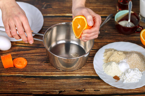 istock Hand squeezes orange juice into a metal bowl 1393870195