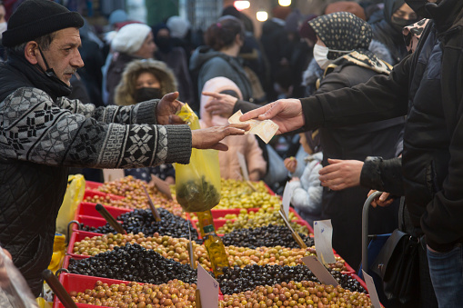 IIstanbul / Turkey - February 2, 2022: Famous street market held every Wednesday in Istanbul's Fatih district. Shopping at the olive counter in the neighborhood market. Horizontal close-up.