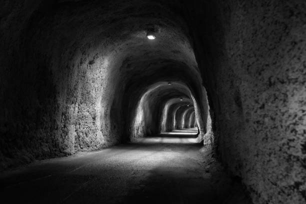 istock View inside a pedestrian tunnel with artificial lighting and raw walls. Tunnel going through the mountains. 1393871291