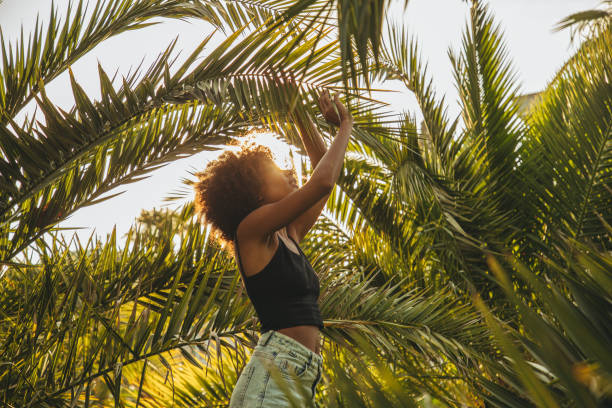 istock Pretty young afro woman among palm trees 1393871817