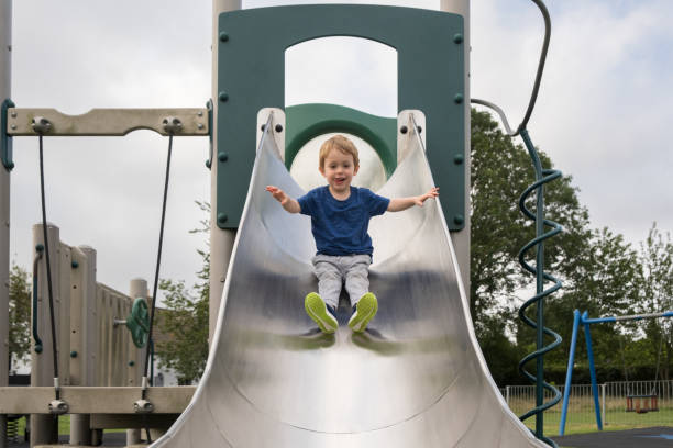 kleiner glücklicher junge oben auf der rutsche im park - playground cute baby blue stock-fotos und bilder