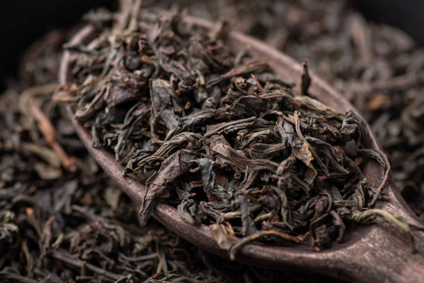 istock Black dried tea leaves in wooden spoon 1393876557