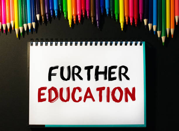 istock Inscription FURTHER EDUCAYION in a notebook. Composition with various school supplies on a black background. Creative background, layout. View from above. Marketing concept. 1393879513