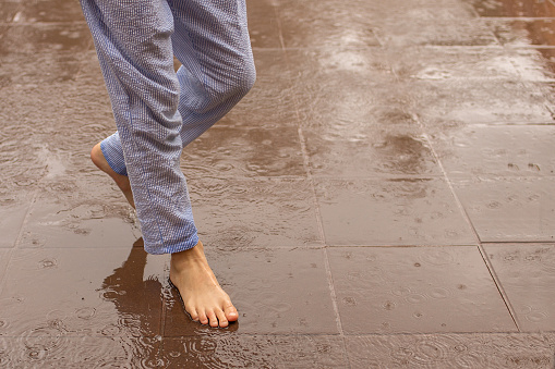 Girl walks barefoot on a tile wet from the rain