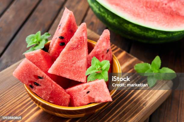 Sliced Watermelon Decorated With Mint Leaves On Brown Wooden Background Closeup Selective Focus Stock Photo - Download Image Now