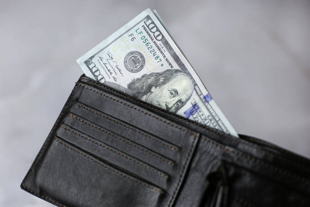 istock 100 dollars banknote in a dark leather wallet on a light background 1393880968