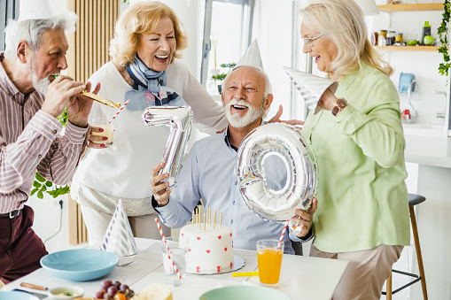 Four senior cheerful friends celebrating 70th birthday at home