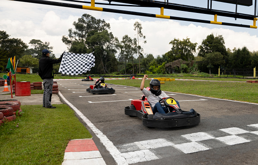 Competitive Latin American man racing in go-carts and crossing the finishing line as a winner
