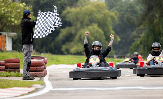 Competitive Latin American Man racing in go-carts and crossing the finishing line as a winner