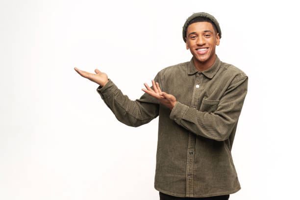 istock Good looking joyful man presenting advertising area on his palm and pointing to copy space, holding empty place for commercial. Indoor studio shot isolated on white 1393884659