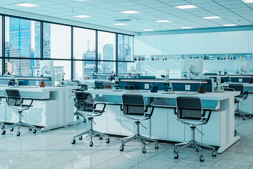 Modern Empty Science Laboratory With White Desks, Microscopes, Scientific Equipments And Cityscape From The Window