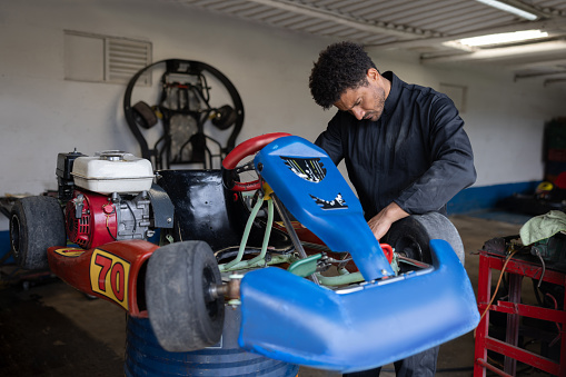 Latin American mechanic working at a car garage fixing a go-cart