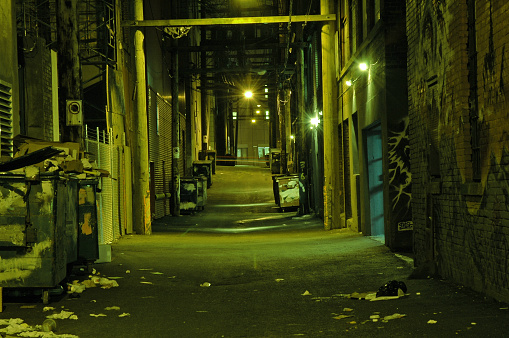 A seedy looking alley at night, dark, dangerous, seedy and dirty.
