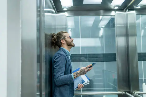 Businessman using smartphone in elevator.