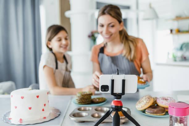 istock Female cute little vlogger live broadcasting tutorial with her mother and giving cooking advice to her followers 1393887847