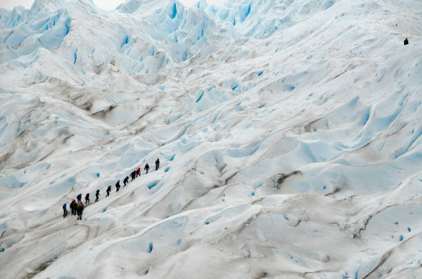 Tourists wearing crampons traverse a stunning glacier in patagonia, chile, surrounded by majestic mountains and breathtaking icy landscapes