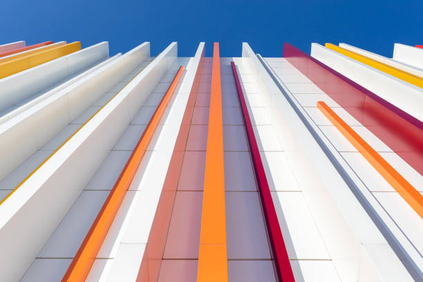 a fragment of a white wall decorated with multicolored plastic on a blue sky background. Vertical perspective