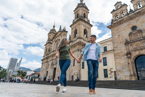 Happy couple holding hands at the Plaza de Bolivar while sightseeing in Bogota - travel concepts