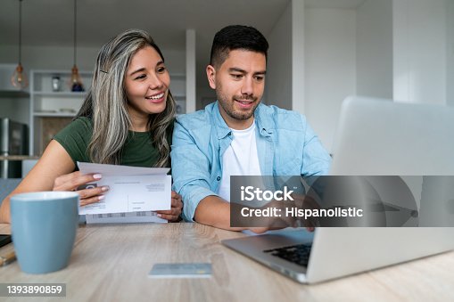 istock Happy couple at home paying bills online 1393890859