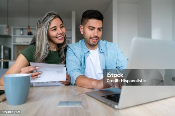 Happy Couple At Home Paying Bills Online Stock Photo - Download Image Now - Financial Bill, Home Finances, Paying