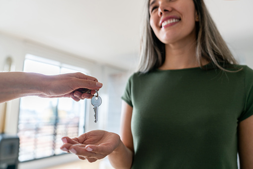 Real estate agent giving the keys of her new house to a happy Latin American woman - home ownership concepts
