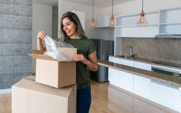 Woman moving house and packing in boxes using bubble pack