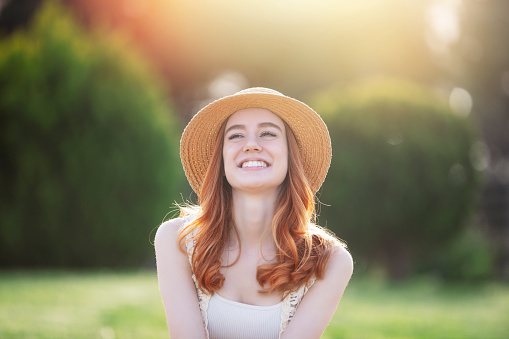 portrait of beautiful cheerful woman in summer season , in public park and at sunset