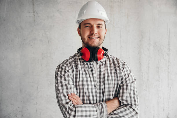 constructor masculino encantado en casco sobre fondo gris - arms crossed audio fotografías e imágenes de stock