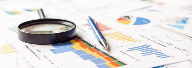 Photo of Magnifier and pen on charts graphs paper. Financial development. Banner